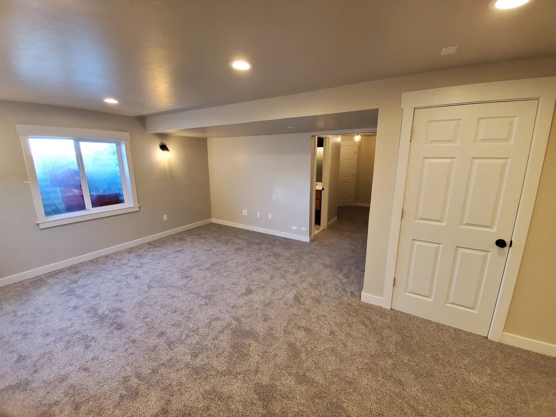 After: basement finishing in Utah, from bare drywall and concrete to a carpeted family room with recessed lights and wall sconces