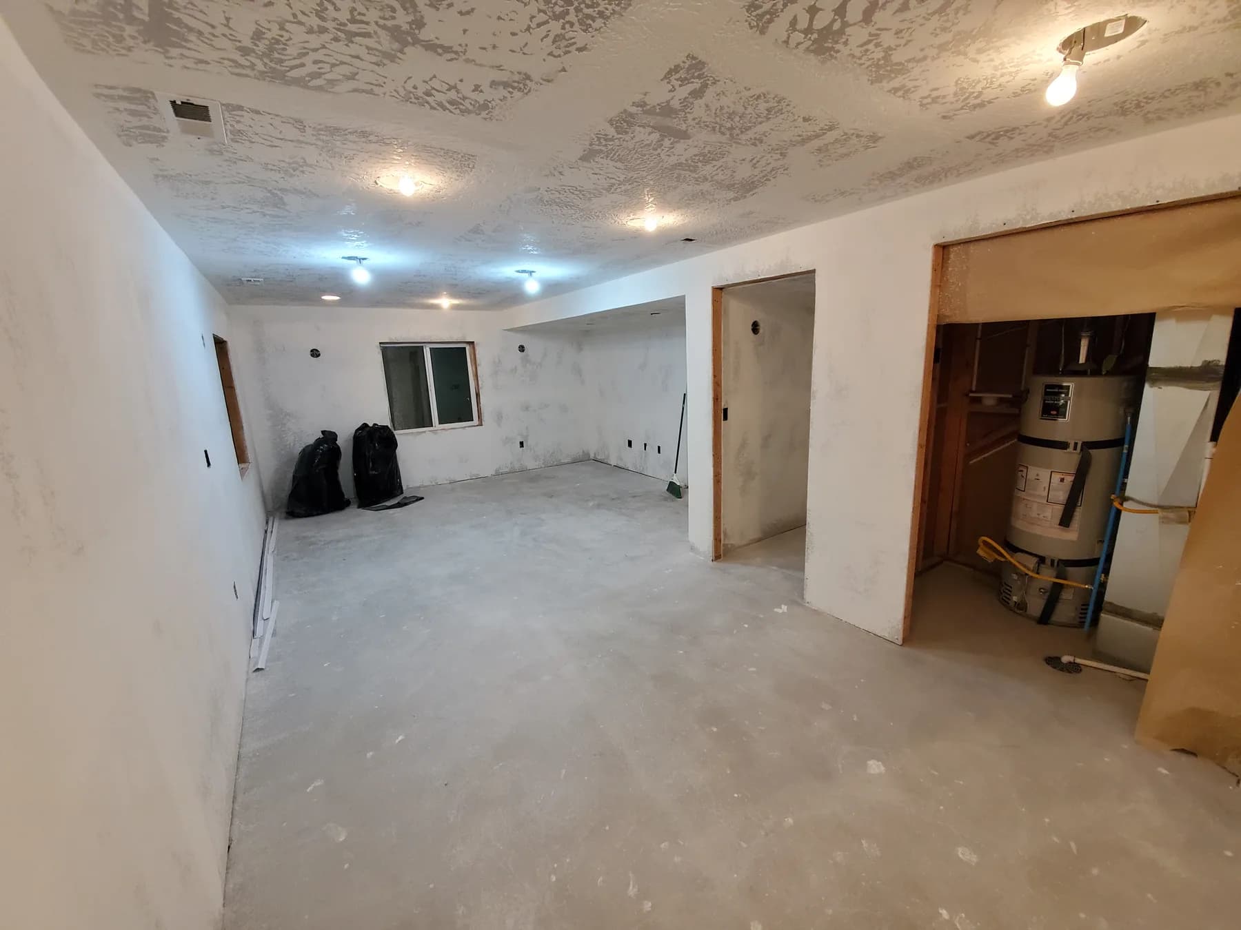Before: basement finishing in Utah, from bare drywall and concrete to a carpeted family room with recessed lights and wall sconces