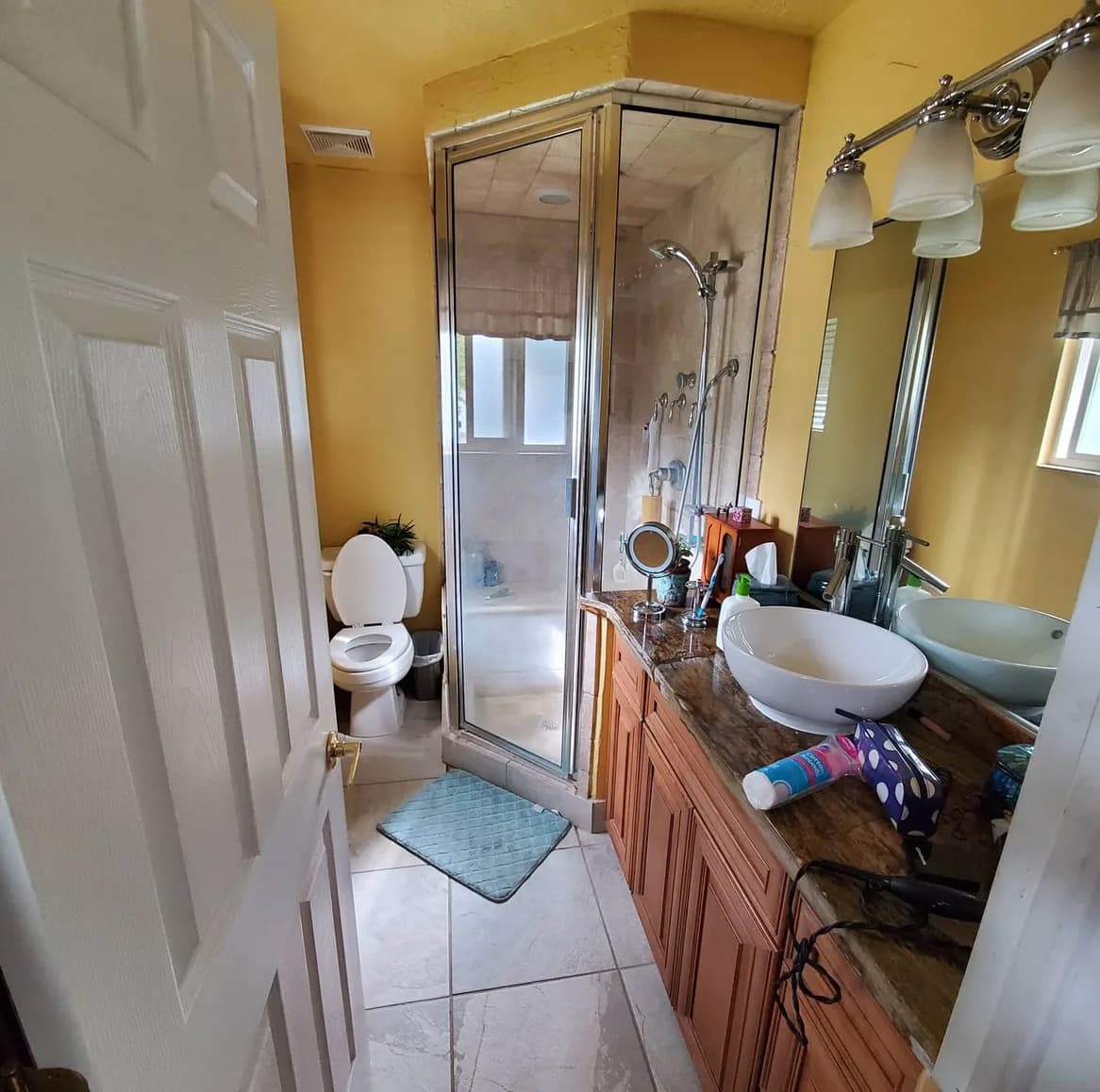 Before — bathroom remodel in Utah, from a yellow bathroom with a framed corner shower to a navy vanity and frameless sliding glass shower