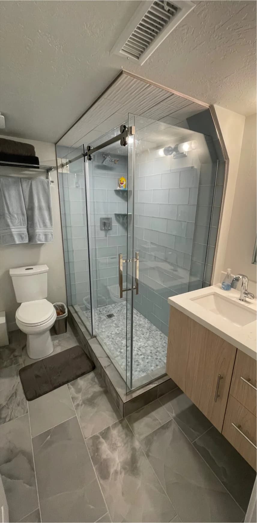 After: bathroom remodel in Utah, from a dated basement bathroom to a glass shower with a floating wood vanity