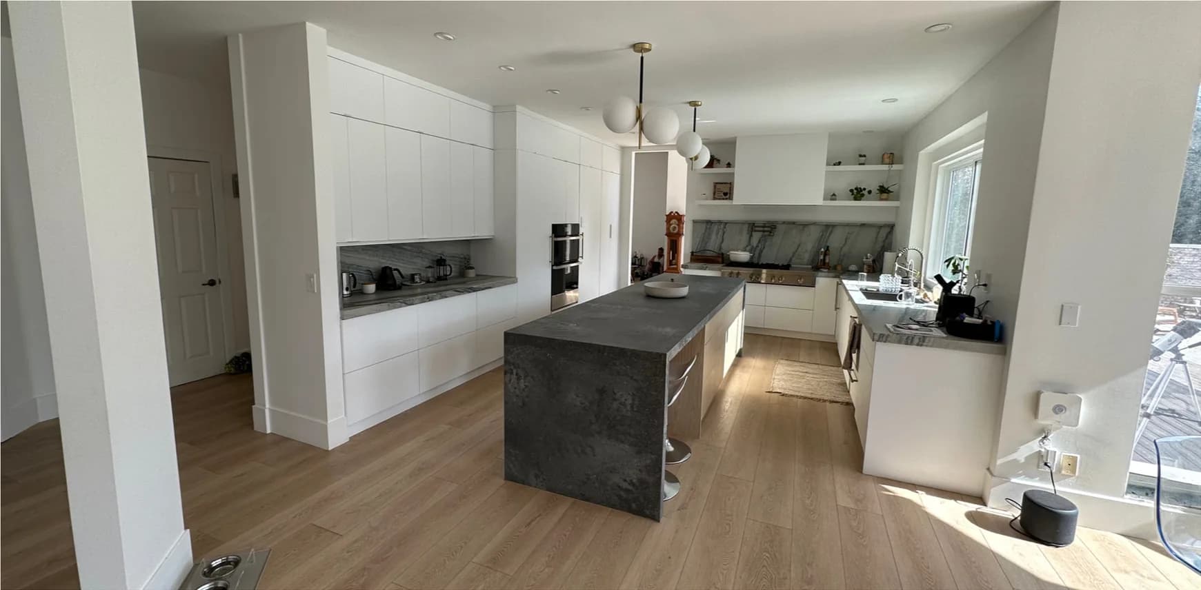 After — kitchen remodel in Utah, from a traditional white kitchen with dark granite to a modern white kitchen with a waterfall quartz island